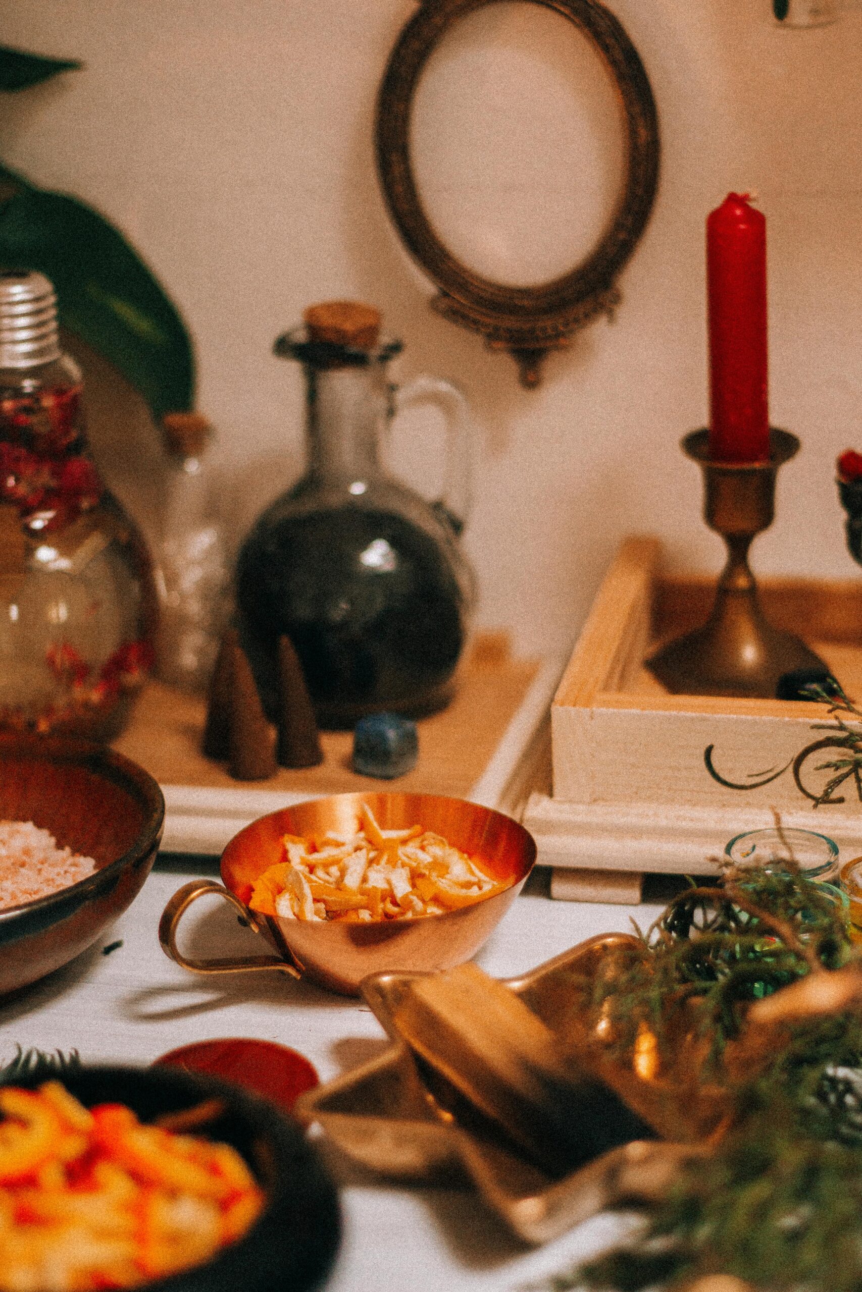 Cozy herbal apothecary table with candles, spices, and vintage decor.
